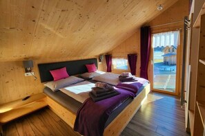 A wooden cabin bedroom with a bed, pillows, a bench, and a window. - Cabin in Murau with swimming pool (Murau)