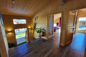 A wooden interior with a staircase, a ski rack, and a view of the outside. - Cabin in Murau with swimming pool (Murau)