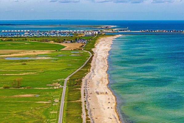 Eine Luftaufnahme einer Küstenregion mit Strand, einer Straße und einer Reihe Strandhäuser.