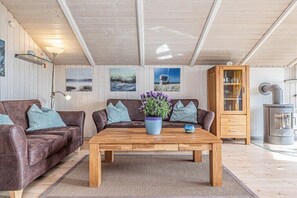 Ein gemütliches Wohnzimmer mit zwei braunen Ledersofas, einem Holztisch und einer Vitrine mit Glastüren.