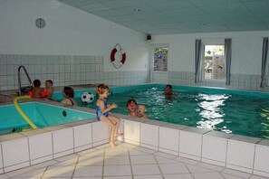 Ein Hallenbad mit gefliesten Wänden, einer sichtbaren Uhr und einem Rettungsring an der Wand.