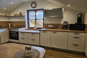 Eine moderne Küche mit weißen Schränken, einem eingebauten Backofen, einer Kaffeemaschine und einer Mikrowelle.