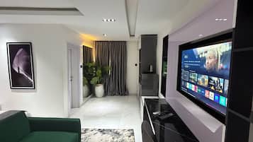 A modern living room with a green sofa, a large flat-screen TV, and a minimalist design.