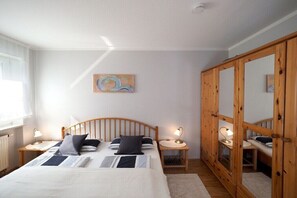 Ein Schlafzimmer mit einem Bett, Nachttischen, einem Spiegel und einem Bild an der Wand.