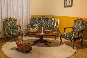 A room with a round table, two chairs, a decorative bird, a vase with flowers, and a candle. - Guesthouse "Auf der Burg" OG (Andernach)