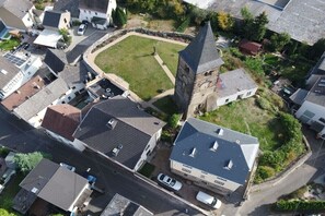 An aerial view of a residential area with houses, a central grassy square, and a prominent tower-like structure. - Guesthouse "Auf der Burg" OG (Andernach)