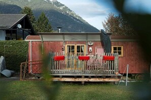 Ein rotes Holzgebäude mit Veranda, Fenstern und einer Satellitenschüssel.