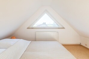 Ein Schlafzimmer mit einem Einzelbett, einem Heizkörper und einem Oberlicht.