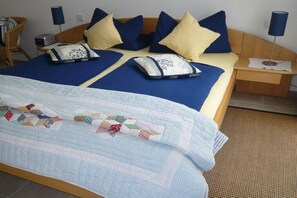 Ein Bett mit blau-gelber Bettwäsche, einer Tagesdecke und zwei Nachttische mit Lampen.