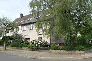 A two-story house with a sloped roof, a garage, and a driveway. - Holiday apartment in Essen with swimming pool (Essen)