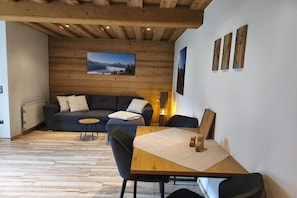Ein modernes Wohnzimmer mit Holzboden, einer Couch, einem Esstisch und einem Kamin.