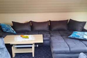 A sectional sofa with a wooden coffee table, a small drawer unit, and a blue and white patterned pillow. - Holiday apartment with 1 bedroom (Prerow\/Ostseebad)