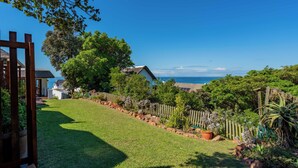A well-maintained garden with a wooden fence, a variety of plants, and a view of the sea. - Cycads On Sea (Saint Francis Bay)