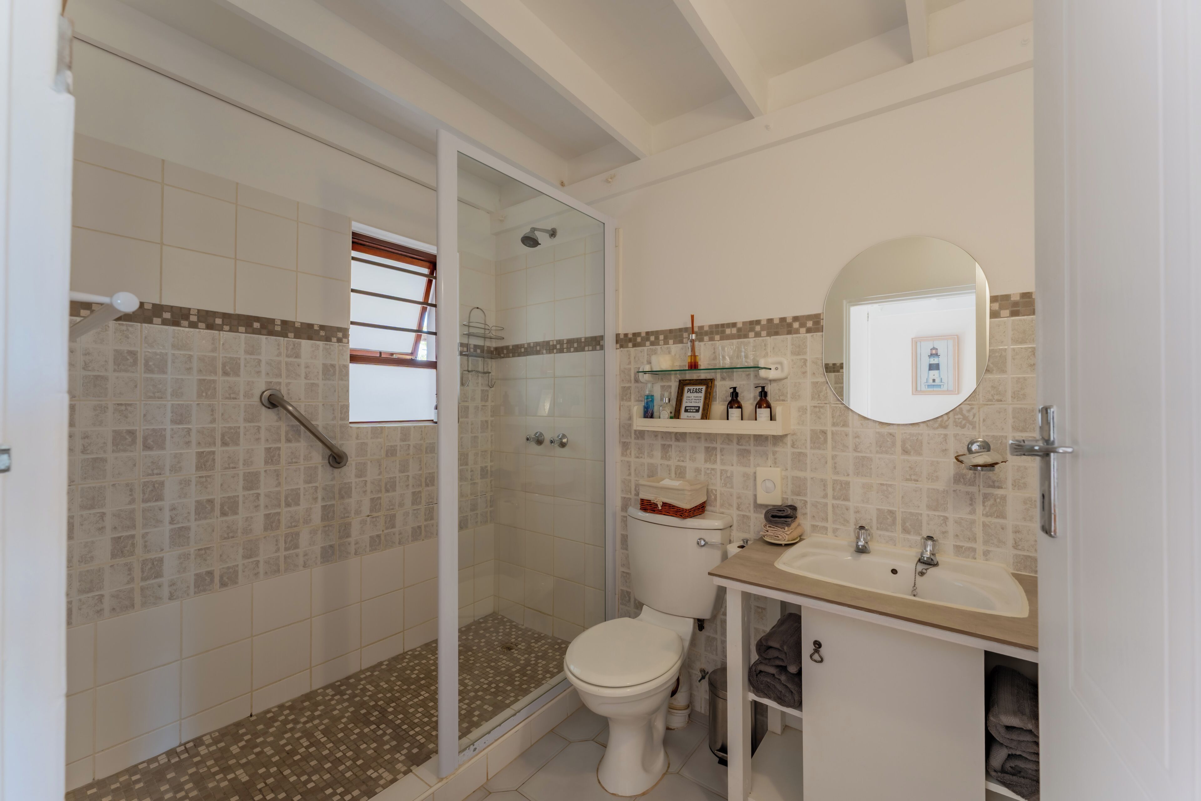 Une salle de bain équipée d’une douche, de toilettes, d’un lavabo et d’un miroir.