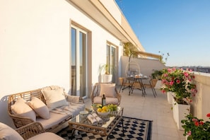 A balcony with wicker furniture, a dining table, and potted plants. - Penthouse with Terrace in Gargasole SX – Elegant 7th-Floor Retreat with Terrace in Bari (Bari)