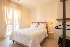 A bedroom with a bed, bedside lamps, a small table, and a window with curtains. - Penthouse with Terrace in Gargasole SX – Elegant 7th-Floor Retreat with Terrace in Bari (Bari)