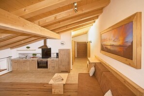 Ein moderner Loft-Wohnraum mit Küche, Holzbalkendecke, einem großen Gemälde und einer gemütlichen Sitzecke.