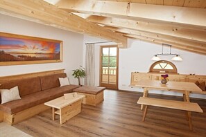 Ein Holzinnenraum mit einer Couch, einem Esstisch und einer Bank.