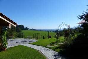 Um jardim com um caminho pavimentado, área de estar ao ar livre e um arco de metal.