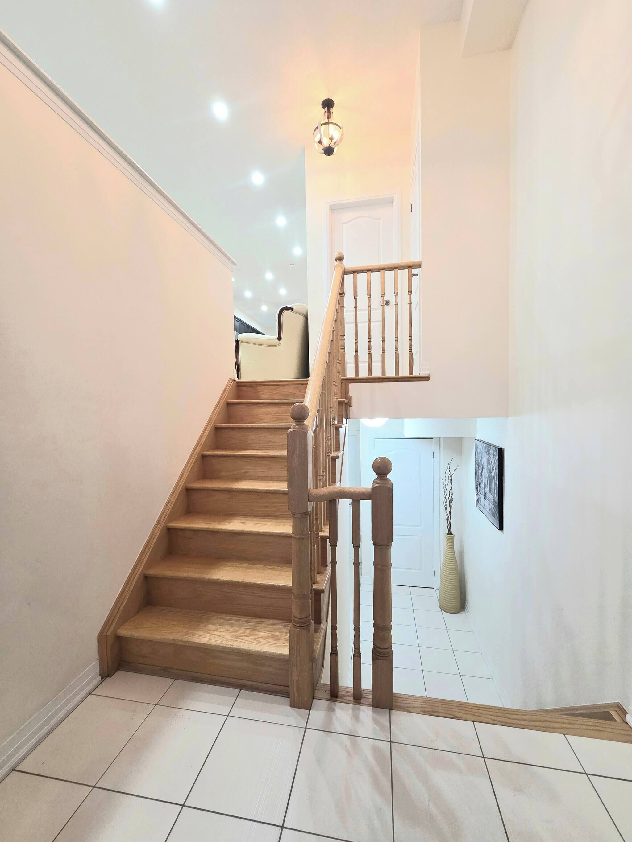 A staircase with wooden railings, a white door at the top, and a light fixture above.