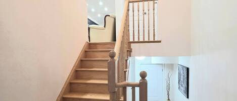 A staircase with wooden railings, a white door at the top, and a light fixture above.