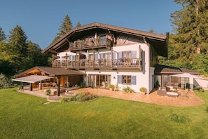 Eine zweistöckige Chalet mit Balkon, überdachter Terrasse und gepflegtem Garten.