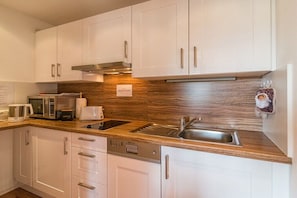 Eine moderne Küche mit weißen Schränken, Edelstahlgeräten und einer Holzrückwand.