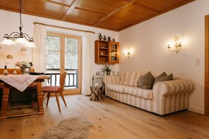 Ein gemütliches Wohnzimmer mit einem Holzesstisch, einem gestreiften Sofa und einem Bücherregal.