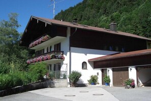Ein zweistöckiges Gebäude mit Balkon, Garage und einer Steinmauer.