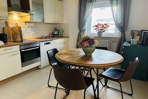 Une cuisine moderne avec une table ronde en bois, des chaises noires et un vase de fleurs.