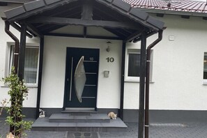 Ein Gebäude mit einer schwarzen Tür, der Hausnummer 10, und einer kleinen Katze auf den Stufen.