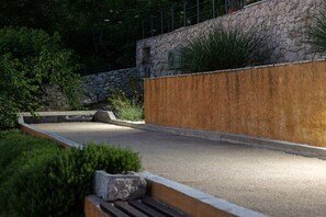 Un espace aménagé comprenant un muret en pierre, un chemin pavé et diverses plantes.