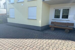 Ein Gebäude mit befestigtem Eingangsbereich, einer Holzbank und einem Fenster mit Rollläden.