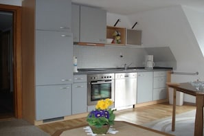 Eine moderne Küche mit grauen Schränken, einem Backofen und einer Kaffeemaschine.