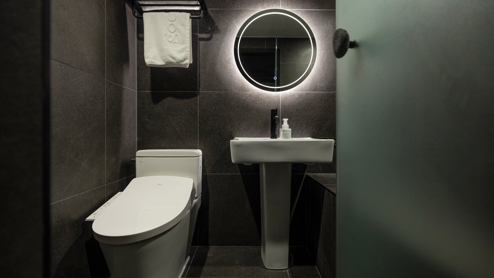 A modern bathroom with a toilet, a sink, and a mirror.