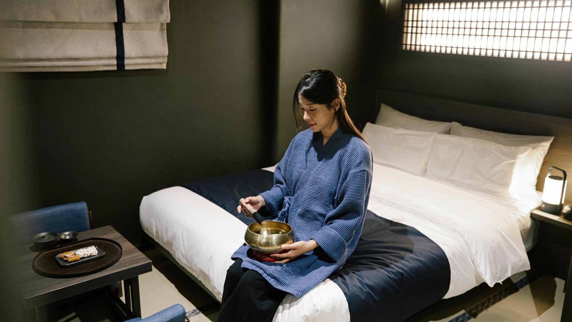 A room with a bed, a small table with a tray, and a bowl.