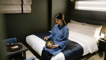 A room with a bed, a small table with a tray, and a bowl.