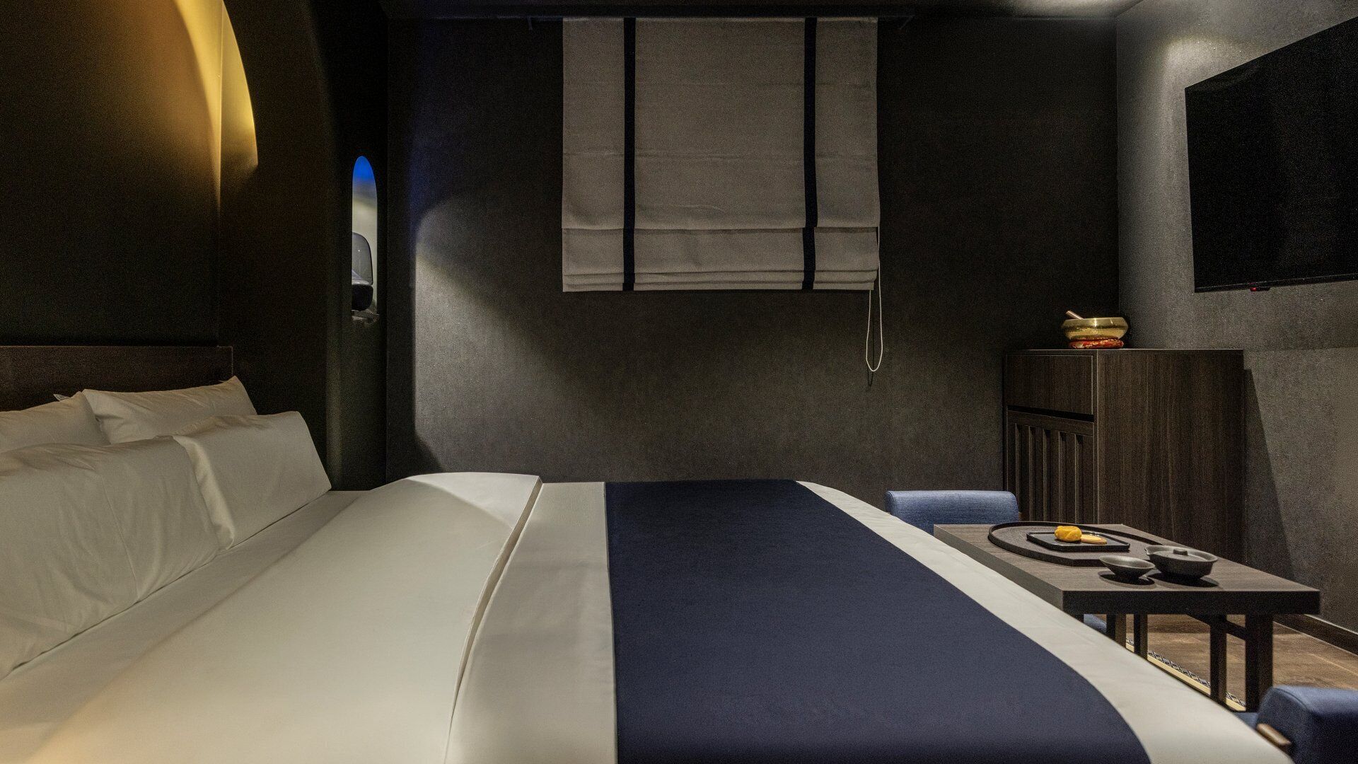 A hotel room with a bed, a desk, and a chair.