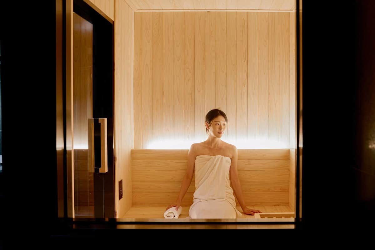 Una persona sentada en una sauna de madera con una toalla alrededor del cuerpo.
