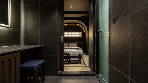 A narrow hallway leading to a bedroom with a bed, bedside table, and bench. - Cave Ryokan Hotel by Anook Incheon Bupyeong Station (Incheon)