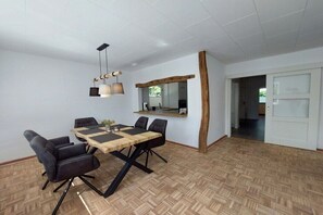 A dining area with a wooden table and chairs, a hanging light fixture, and a mirror on the wall. - Unique landscape view (Stoltebüll)