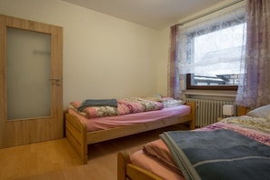 A bedroom with two single beds, a wooden wardrobe, a window with curtains, and a radiator. - in the Eifelwiese house (Monschau-Höfen)