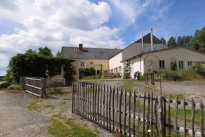 Ein zweistöckiges Gebäude mit Kiesweg, Holzzaun und Metalldrahtgitter.
