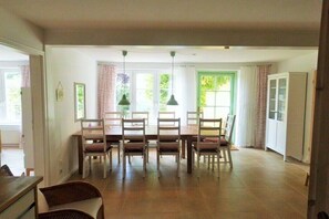 Ein Essbereich mit Tisch und Stühlen, einem Fenster mit Vorhängen und einer Tür mit Schrank.