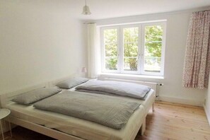 Ein Schlafzimmer mit Bett, Fenster und Heizkörper.