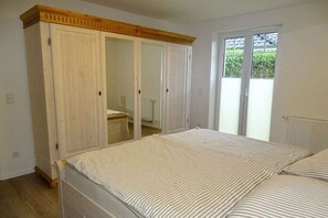 Ein Schlafzimmer mit Bett, Kleiderschrank und einer Schiebetür zum Außenbereich.