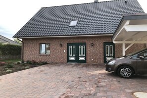 Ein Ziegelhaus mit dunklem Ziegeldach, einer grünen Tür und einem Auto auf der Auffahrt.