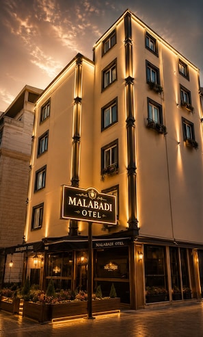 Un hotel de diverses plantes amb un cartell ben visible que diu 'MALABADI HOTEL'.