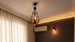 A hotel room with a bed, bedside table, nightstand, and an air conditioning unit. - ÖZ MALABADİ OTEL (Mersin)