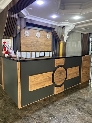 Un comptoir d’accueil au design moderne, avec des éléments en bois et des touches de noir, agrémenté d’une horloge, de certificats encadrés et d’une décoration sur le thème du Père Noël.